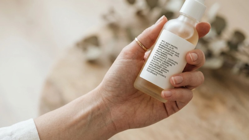 Hand holding frosted glass bottle showing ingredient label